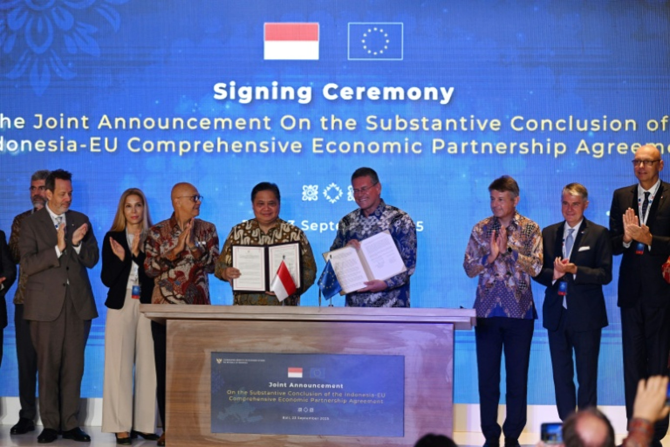 Le ministre indonésien de l'Economie, Airlangga Hartarto (au centre à g.), et le commissaire européen au commerce, Maros Sefcovic (au centre à d.), posent sur scène après avoir paraphé l'accord de libre-échange entre l'Indonésie et l'UE sur l'île indonésienne de Bali, le 23 septembre 2025 © Sonny TUMBELAKA