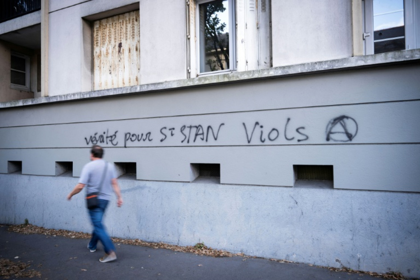 Un homme passe devant un graffiti dans une rue proche de l'entrée du lycée privé catholique et du Collège Saint-Stanislas à Nantes, le 29 août 2025 © Loic VENANCE
