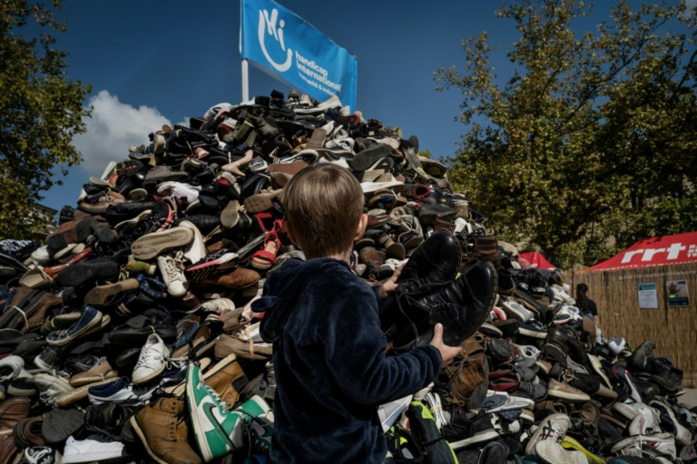 Un enfant jette une paire de chaussures à l'occasion du 30e anniversaire de la pyramide de chaussures de Handicap international (HI), le 27 septembre 2025 à Lyon © JEFF PACHOUD