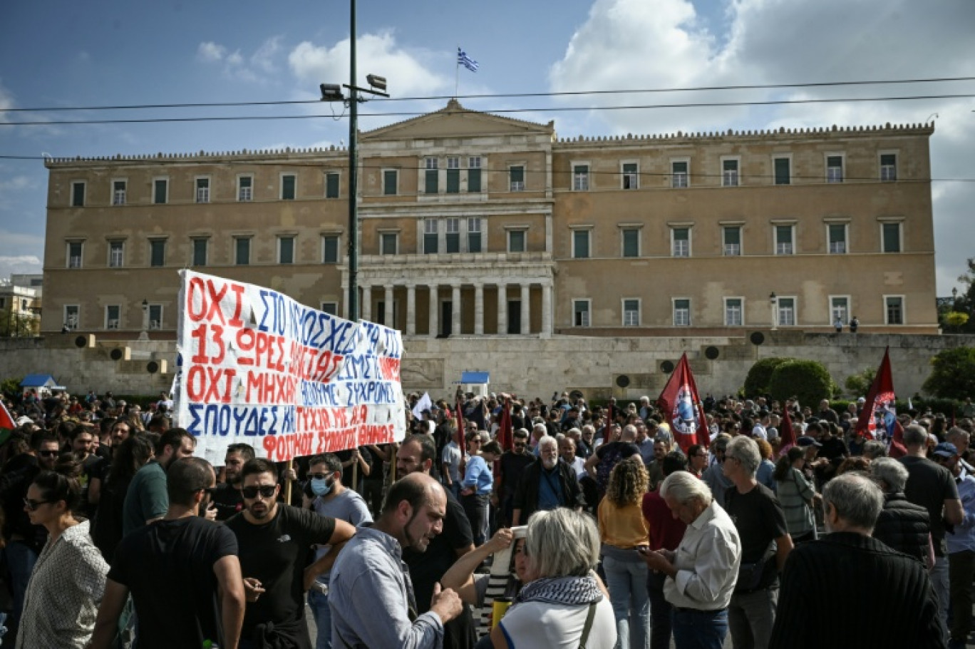 Des manifestants sont regroupés devant le Parlement grec lors d'une grève contre une réforme permettant des journées de travail de 13 heures, le 14 octobre 2025 à Athènes © Aris MESSINIS