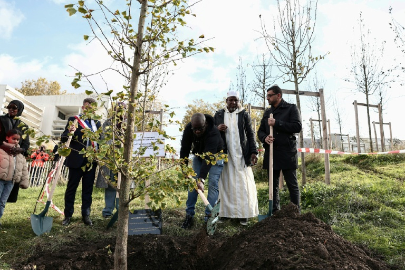 Le frère de Bouna, Siyakha (g) et son père Seydou (c) participent à la plantation d'un arbre près du lycée Robert Doisneau lors d'une cérémonie de commémoration marquant le 20e anniversaire de la mort des adolescents Zyed Benna et Bouna Traoré, à Clichy-sous-Bois, le 27 octobre 2025 en Seine-Saint-Denis © Thibaud MORITZ