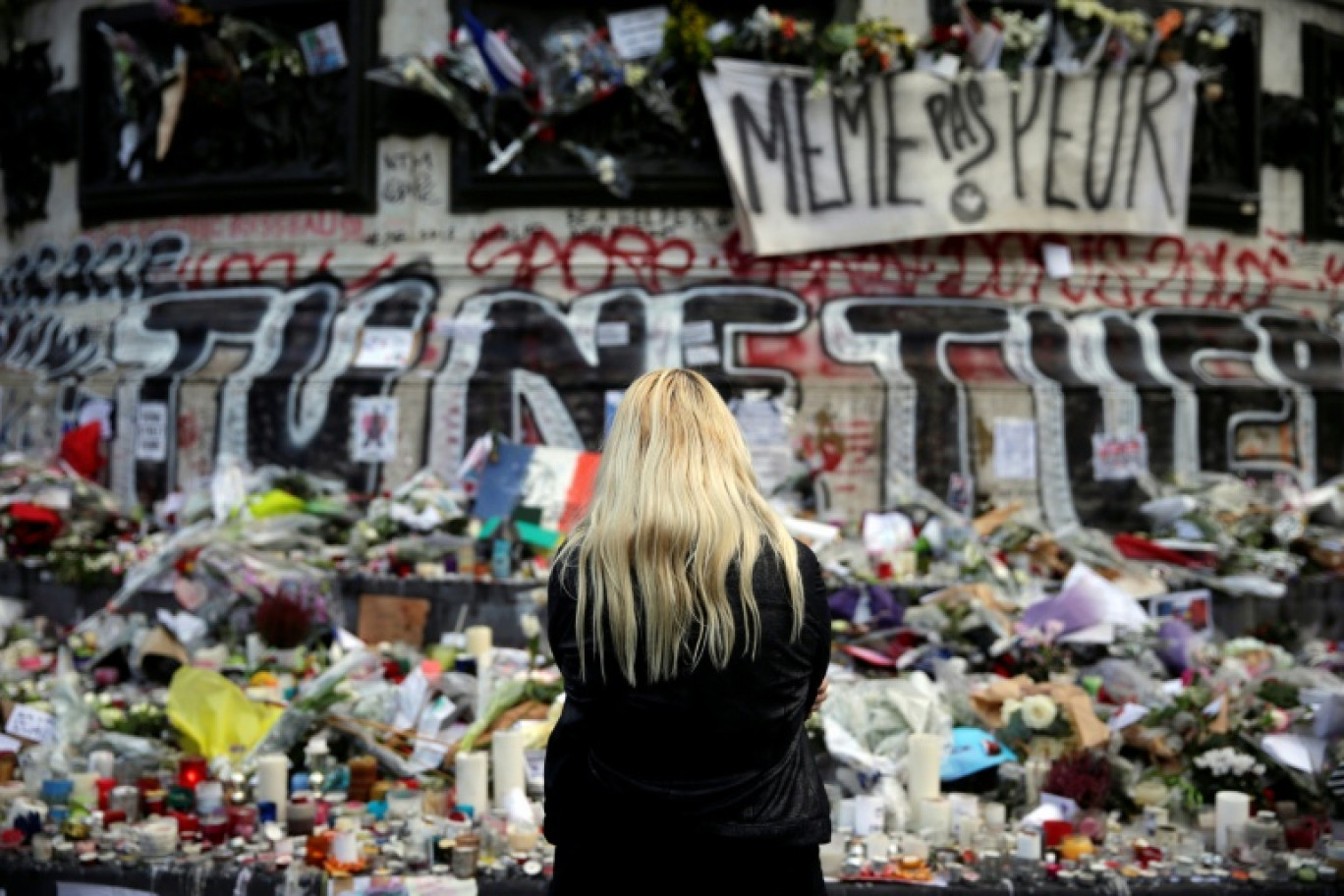 Une femme se recueille devant un mémorial improvisé composé de fleurs, de bougies et de messages, place de la République à Paris, le 17 novembre 2015, en hommage aux victimes des attentats du 13 novembre 2015 © Kenzo TRIBOUILLARD