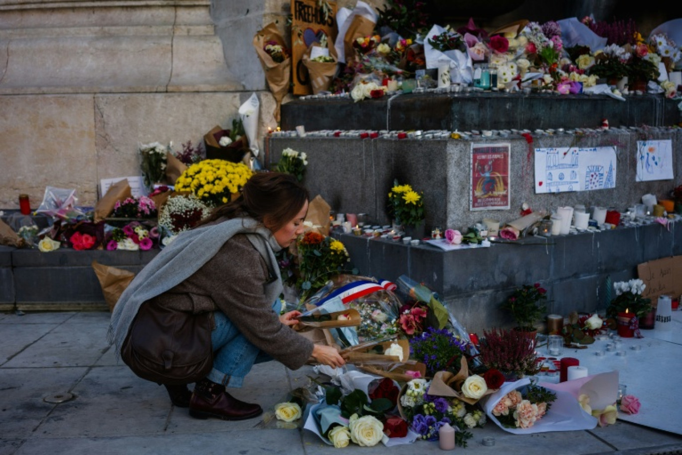 Une femme dépose des fleurs en hommage aux victimes du 13 novembre 2015, Place de la République à Paris, le 11 novembre 2025 © Dimitar DILKOFF