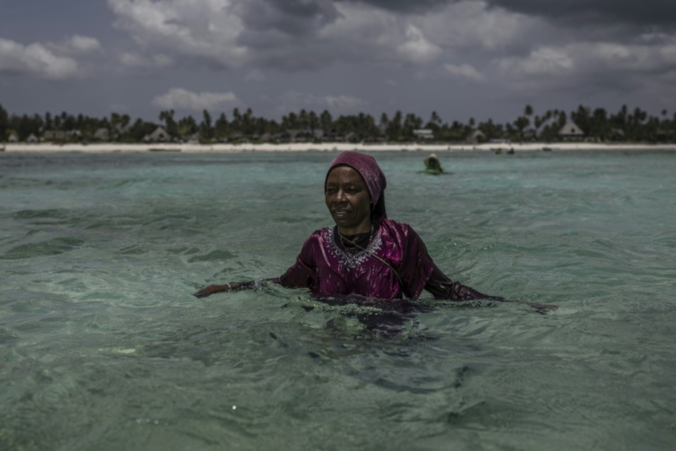 Une agricultrice de la Coopérative des producteurs d'éponges de Zanzibar, une organisation dirigée par des femmes, observe les environs à son arrivée à sa ferme au large de Jambiani (Tanzanie), le 25 octobre 2025 © MARCO LONGARI