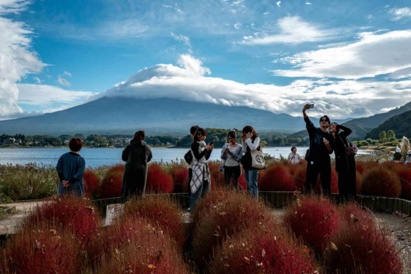 Des touristes prennent des photos avec le mont Fuji couvert de nuages en arrière-plan depuis le parc Oishi, dans la ville de Fujikawaguchiko, au Japon, le 18 octobre 2025 © Philip FONG