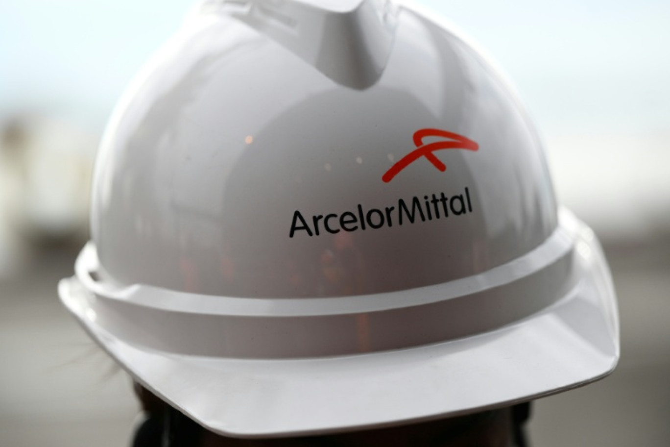 Un employé porte un casque comportant le logo d'ArcelorMittal, à Fos-sur-mer, le 22 février 2023 © Christophe SIMON