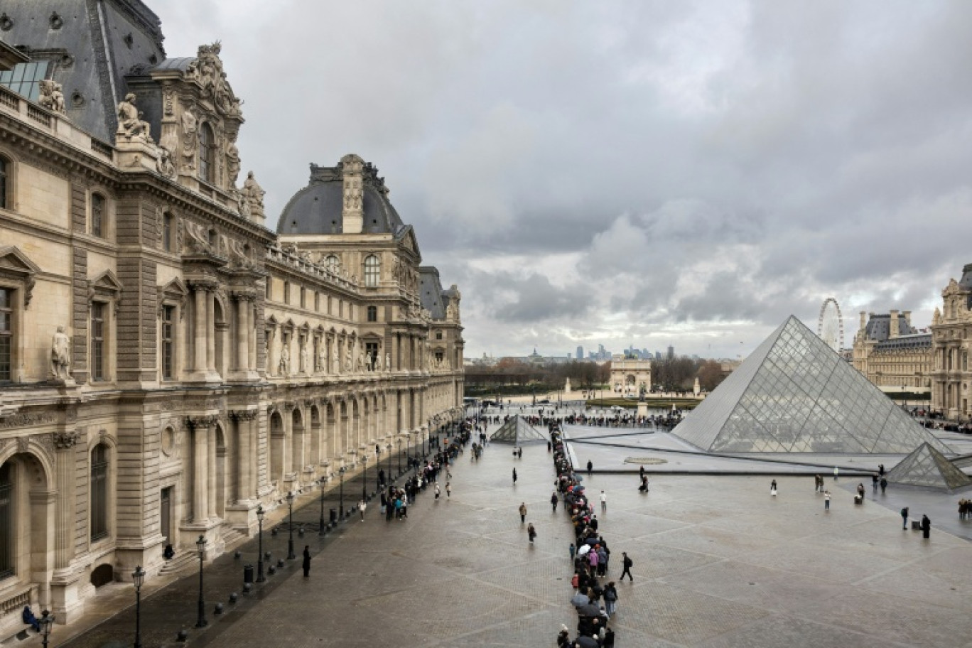 Des visiteurs font la queue, près de la pyramide conçue par l'architecte sino-américain Ieoh Ming Pei, pour entrer au musée du Louvre, le 19 novembre 2025 à Paris © Sébastien DUPUY