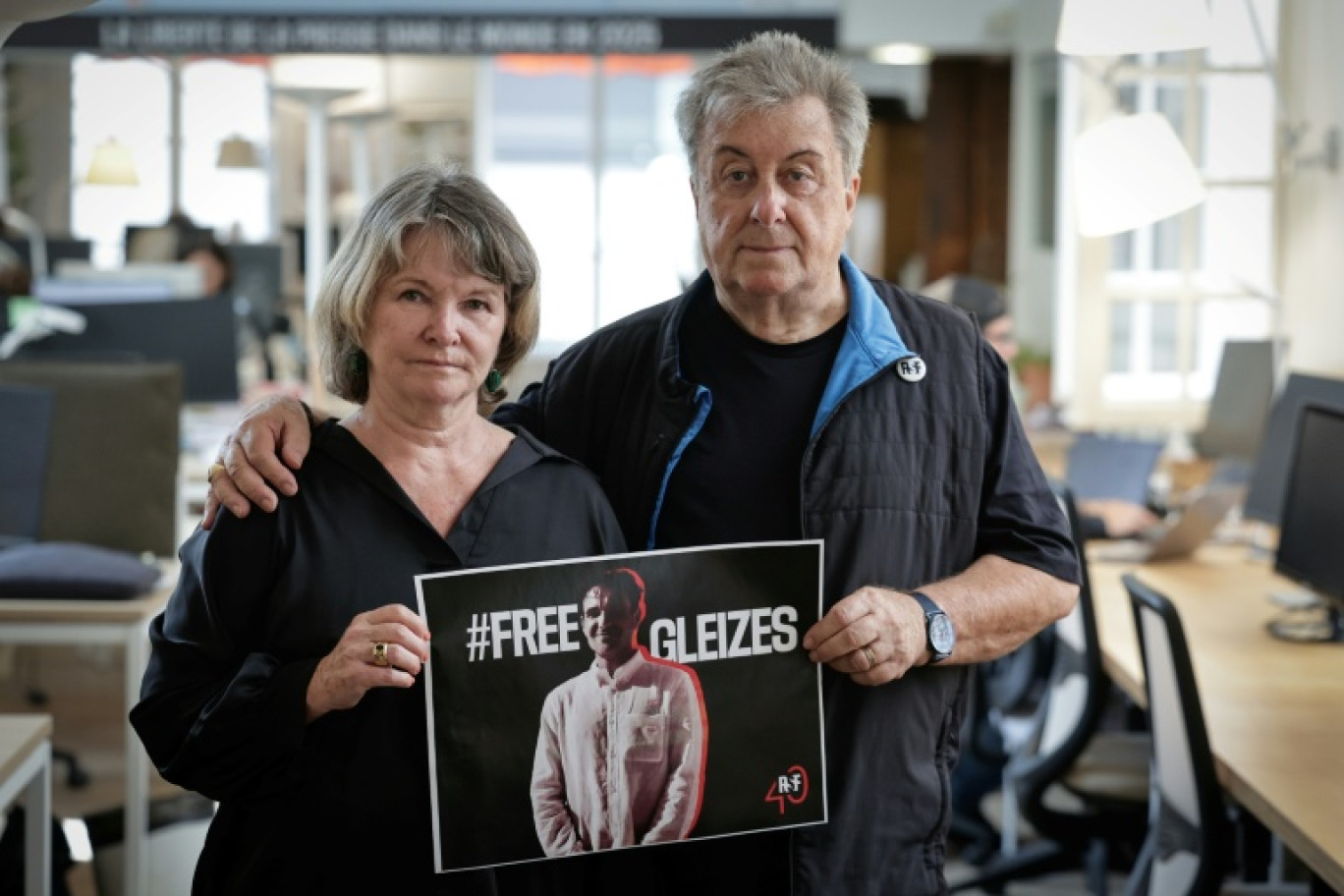 La mère du journaliste Christophe Gleizes, Sylvie Godard, et son beau-père Francis Godard tiennent avec une affiche appelant à sa ibération, le 27 août 2025 à Paris © STEPHANE DE SAKUTIN