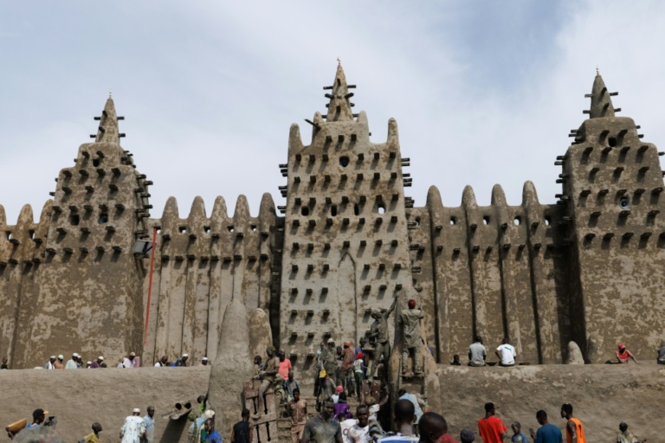Des personnes utilisent du banco, un enduit de terre, pour le crépissage annuel de la grande mosquée de Djenné le 12 juin 2025 © OUSMANE MAKAVELI