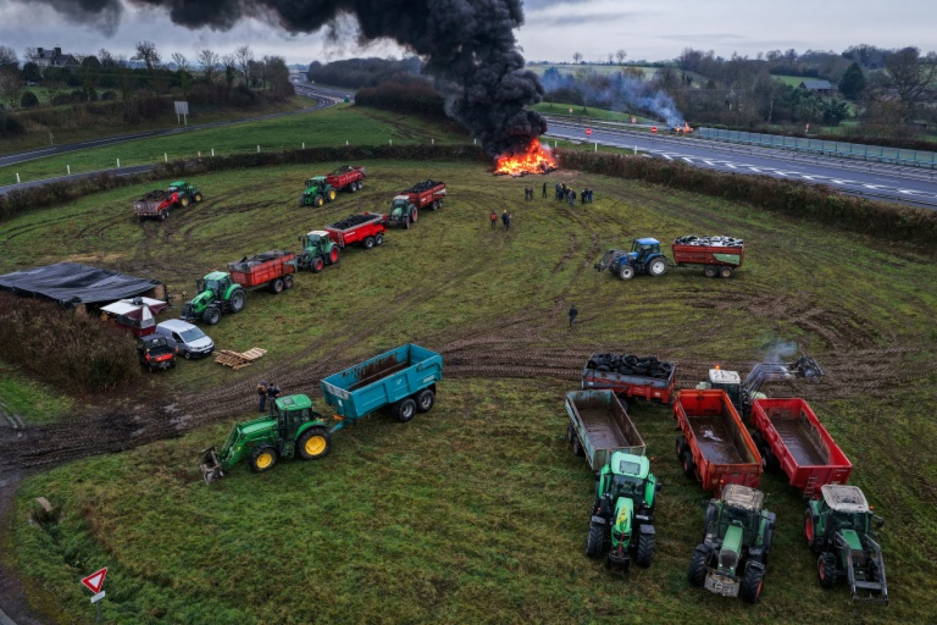 Des agriculteurs allument un feu alors qu'ils participent, avec leurs véhicules, à un blocage d'autoroute, à Poilley, dans l'ouest de la France, le 5 janvier 2026 © Damien MEYER