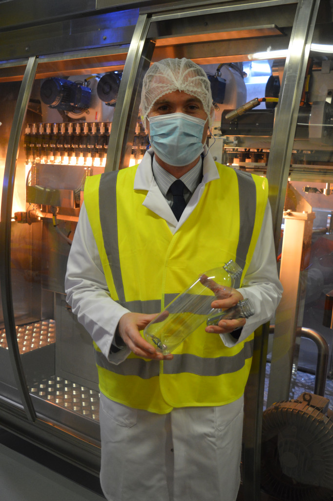 Tom François, le nouveau dirigeant de Hermes Boissons, devant la nouvelle embouteilleuse.