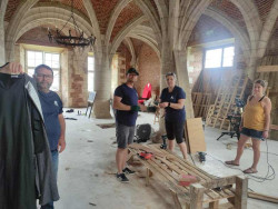 Les bénévoles travaillent dans la salle capitulaire avec principalement du matériel de récupération.